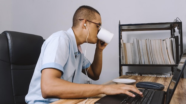 un hombre bebiendo de una taza una persona teniendo un café delante de él mientras trabaja