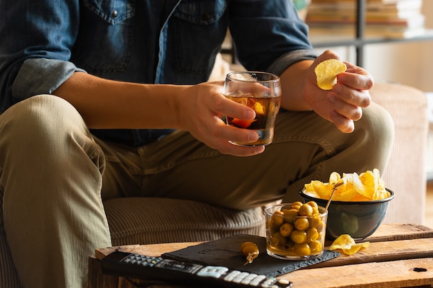 Hombre bebiendo vermú y comiendo bocadillos después del trabajo en casa