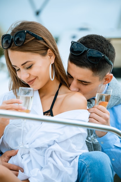 Hombre besando el hombro de una mujer con una copa de champán