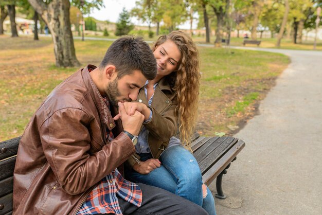 Hombre besando la mano de una mujer contra los árboles en el parque