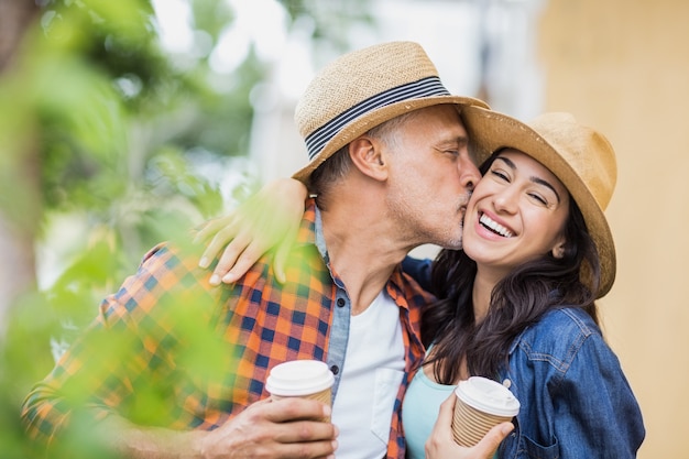 Hombre besando a una mujer alegre con café