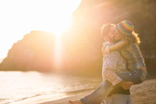 Foto hombre besando a una mujer en la mejilla mientras está de pie en la playa durante la puesta de sol