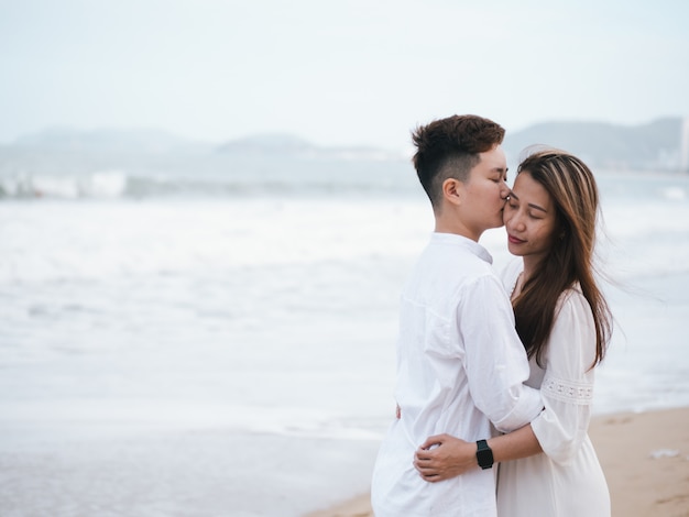 Hombre besando a una mujer en la playa