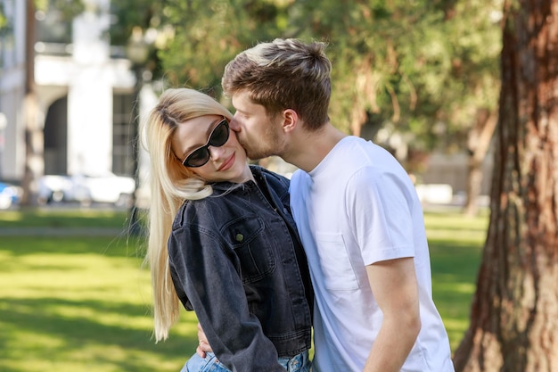 Un hombre besando a su novia en el parque.