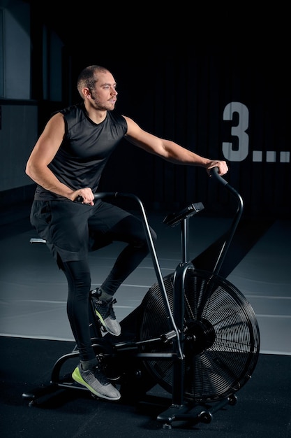 Hombre con bicicleta estática en el gimnasio. Hombre de fitness con bicicleta de aire para entrenamiento cardiovascular en el gimnasio de entrenamiento funcional.