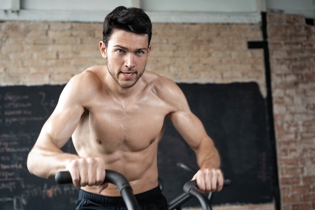 Hombre con bicicleta estática en el gimnasio. Hombre de fitness con bicicleta de aire para entrenamiento cardiovascular en el gimnasio de entrenamiento funcional.