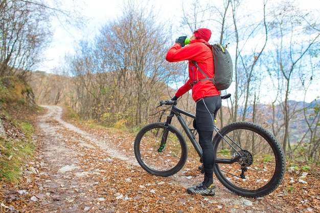 Hombre en bicicleta en la montaña descansa y bebe agua