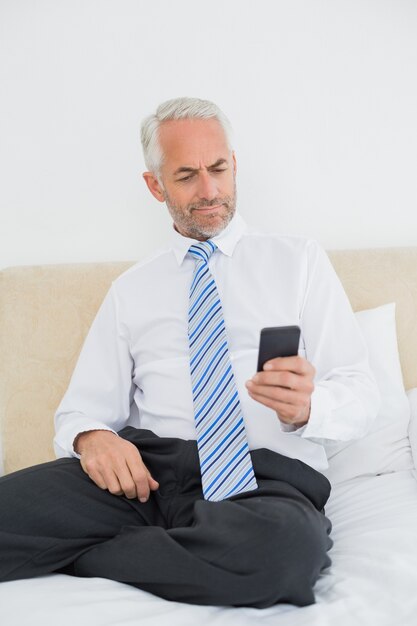 Hombre bien vestido mensajes de texto en la cama