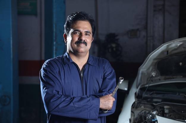 Hombre con bigote en una camisa azul mientras construye un coche en Navneet Sharma India