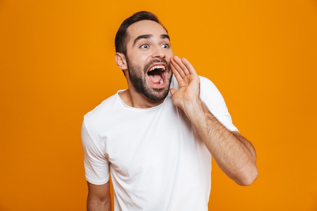 Hombre con bigote en camiseta mientras llama o grita mientras está de pie, aislado en amarillo