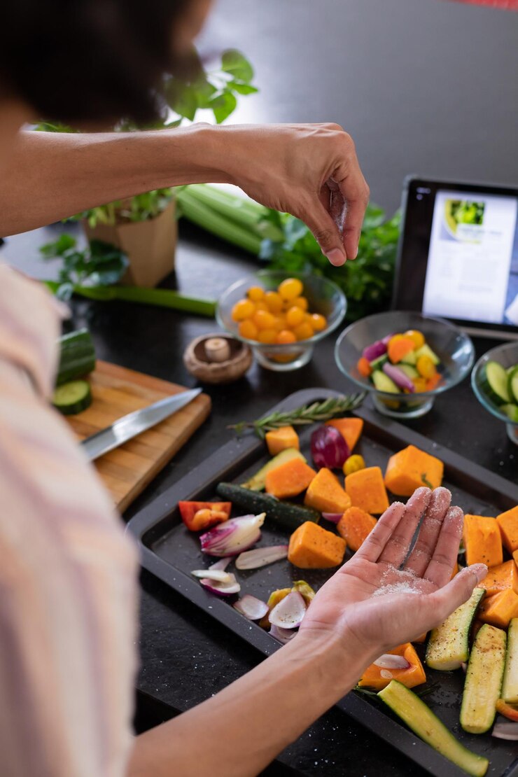 Foto el hombre biracial cocinando, aderezando verduras en la cocina, pasando tiempo de calidad en casa solo, la vida doméstica y el concepto de estilo de vida.
