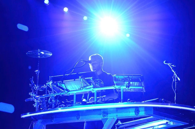 Hombre blanco con barba dj en la noche jugando con una luz principal azul en el fondo