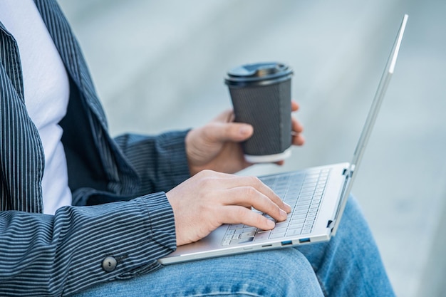 Hombre blogueando en línea con una computadora portátil al aire libre primer plano hombre blogueando en línea en la calle