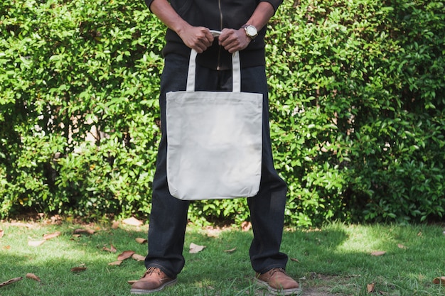 Hombre con bolsa de tela de lona para maqueta, concepto de ecología.