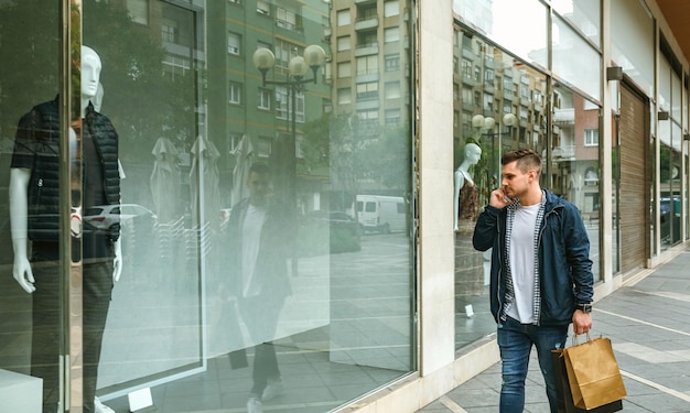 hombre, con, bolsas de compras, en frente, tienda de ropa