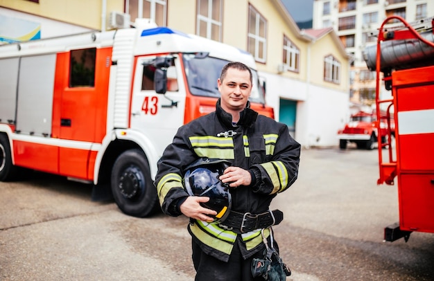 Hombre de bomberos en un traje protector cerca del camión de bomberos Rescate de protección del peligro Estación de bomberos