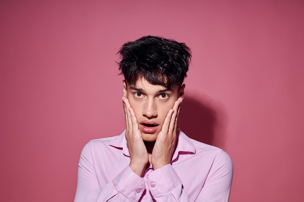 Hombre bonito con una camisa rosa gesticulando con las manos fondo rosa inalterado