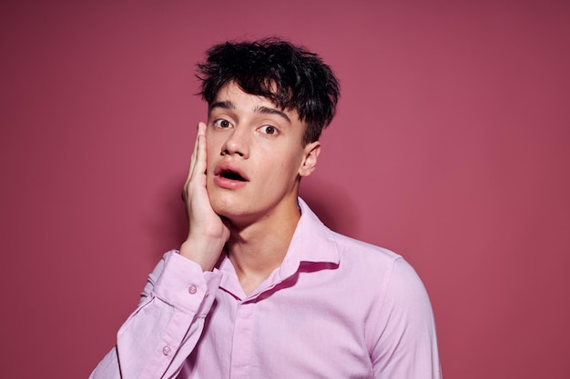 Hombre bonito con una camisa rosa gesticulando con las manos fondo rosa inalterado