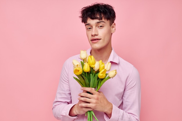 Hombre bonito con una camisa rosa con un ramo de flores gesticulando con su estudio modelo de manos