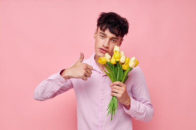 Hombre bonito con una camisa rosa con un ramo de flores gesticulando con su estudio modelo de manos