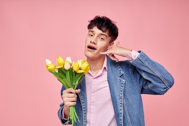 Un hombre bonito con una chaqueta de mezclilla con un ramo de flores un regalo de vacaciones románticas inalterado