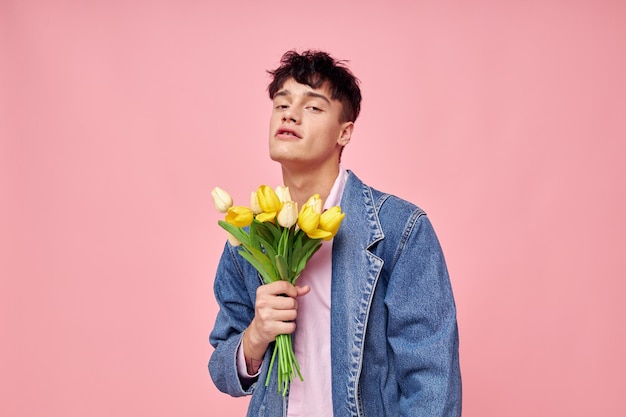 Un hombre bonito con una chaqueta de mezclilla con un ramo de flores un regalo de vacaciones románticas inalterado