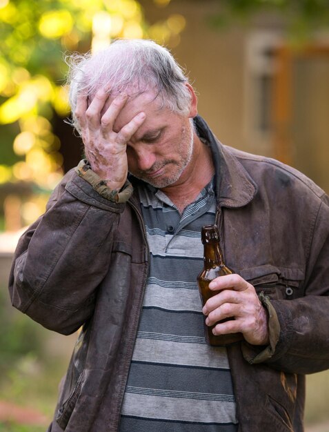 Hombre borracho con botella de cerveza sobre fondo natural