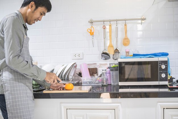 Hombre borroso cocina asiática en la cocina de casa Él manos cortando verduras y cortando frutas