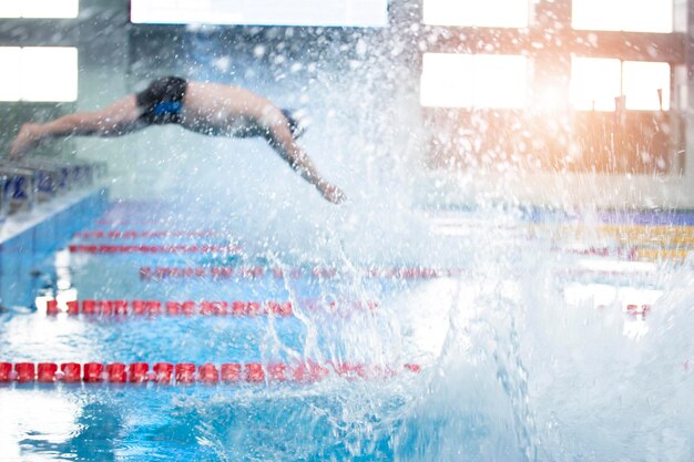 El hombre borroso no es un atleta que se sumerge en la piscina en el agua