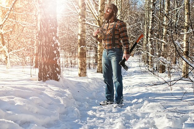 Hombre del bosque de invierno de abedul con hacha