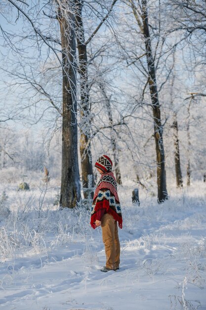 Un hombre en un bosque de invierno solo en un poncho un paseo por la naturaleza