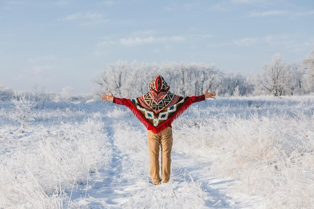 Un hombre en un bosque de invierno solo en un poncho un paseo por la naturaleza