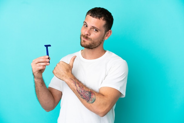 Hombre brasileño afeitándose la barba aislado sobre fondo azul orgulloso y satisfecho de sí mismo