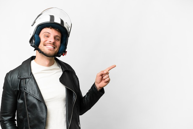 Hombre brasileño con casco de motocicleta sobre fondo blanco aislado señalando con el dedo al costado