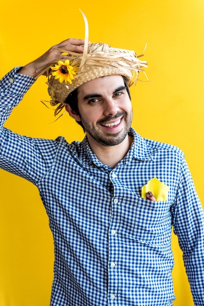 Hombre brasileño feliz con sombrero de paja en la fiesta de junio fiesta sao joao sobre fondo amarillo