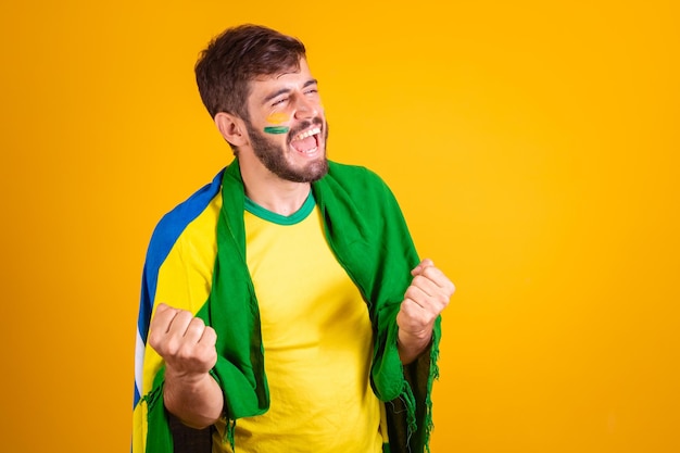 Hombre brasileño latinoamericano animando a brasil en la copa del mundo 2022 fan morena celebrando vibrando feliz gritando gol guapo