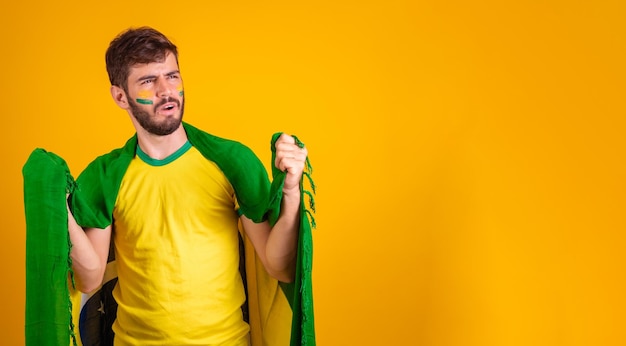 Foto hombre brasileño latinoamericano animando a brasil en la copa del mundo 2022 patriota nacionalista vibrante bandera de brasil animando y saltando símbolo de felicidad alegría y celebración con la bandera de brasil