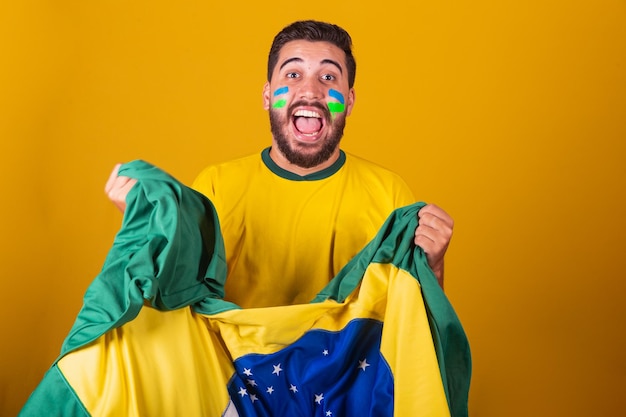 Hombre brasileño latinoamericano animando a brasil en la copa del mundo 2022 Patriota nacionalista Vibrante bandera de brasil animando y saltando símbolo de felicidad alegría y celebración con la bandera de brasil