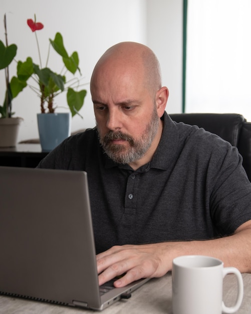 Hombre brasileño de mediana edad que usa una computadora portátil que trabaja en casa