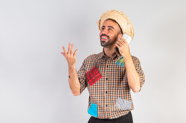Hombre brasileño con ropa de festa junina Arraial Fiesta de San Juan usando un teléfono inteligente