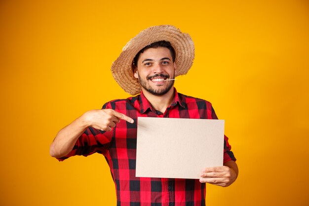 Hombre brasileño con ropa típica de la Festa Junina con cartel