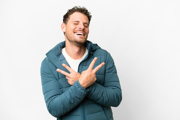 Hombre brasileño sobre fondo blanco aislado sonriendo y mostrando el signo de la victoria