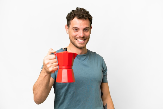 Hombre brasileño sosteniendo una cafetera sobre un fondo blanco aislado con expresión feliz