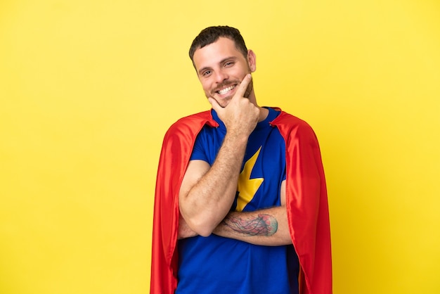 Hombre brasileño de superhéroe aislado sobre fondo amarillo sonriendo