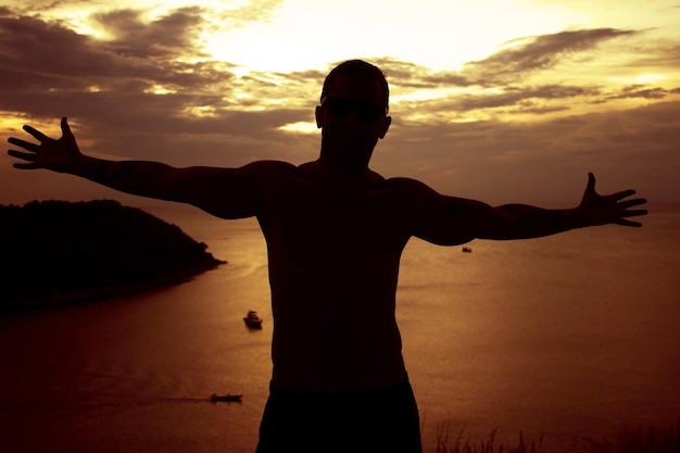 Foto hombre con los brazos extendidos al atardecer