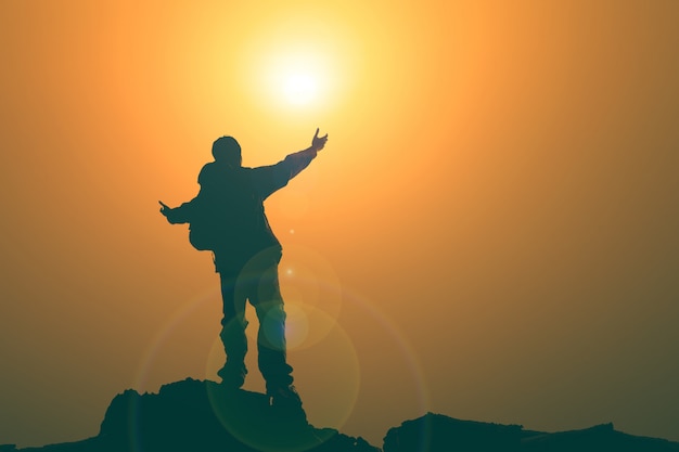 Hombre con los brazos extendidos hacia el cielo al amanecer.