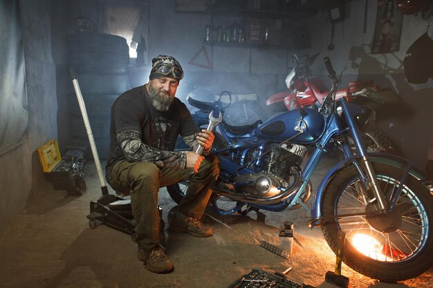 Hombre brutal con una motocicleta en el garaje