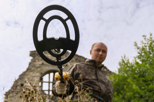 El hombre busca con un detector de metales en las ruinas del edificio una vista desde el suelo