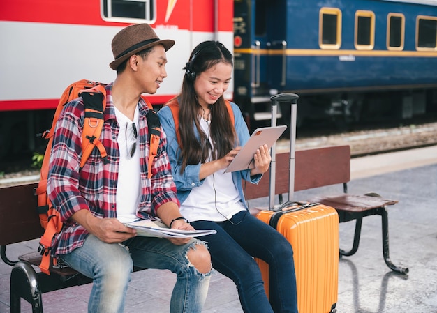 Hombre busca mujer viajero turista usar auriculares con tableta en la estación de tren