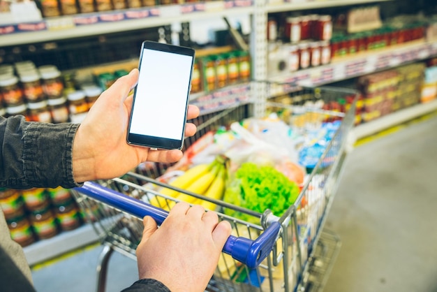 El hombre busca en el teléfono una pantalla blanca de lista de compras para texto